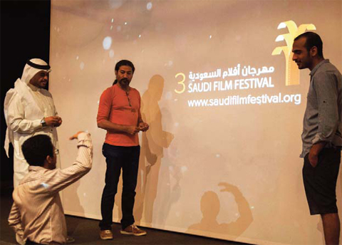 The Saudi film festival director Ahmed Al-Mulla (center) talks with his assistants in front of a screen at the Saudi Cultural Center in Dammam, some 400 km eastern of the capital Riyadh, two days before the opening of the film festival. — AFP photos