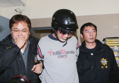 TAIPEI: police escorting a man (C) who allegedly attacked and murdered a Taiwanese toddler along a street.-AFP