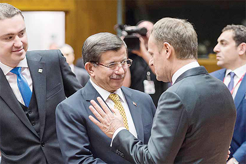 BRUSSELS: Turkish Prime Minister Ahmet Davutoglu (center left) shakes hands with European Council President Donald Tusk, center right, during a round table meeting at an EU summit in Brussels yesterday. —AP