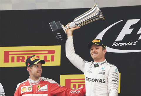 SHANGHAI: Mercedes AMG Petronas F1 Team’s German driver Nico Rosberg (R) celebrates on the podium after winning the Formula One Chinese Grand Prix as second-placed Ferrari driver Sebastian Vettel (L) of Germany congratulates him in Shanghai yesterday. — AFP