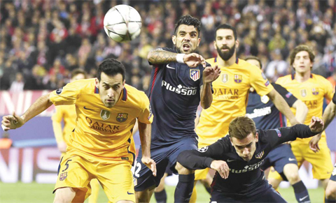 MADRID: Barcelona’s midfielder Sergio Busquets (L) heads a ball next to Atletico Madrid’s Argentinian midfielder Augusto Fernandez (C) and Atletico Madrid’s French forward Antoine Griezmann (R) during the Champions League quarter-final second leg football match Club Atletico de Madrid VS FC Barcelona at the Vicente Calderon stadium in Madrid yesterday. — AFP