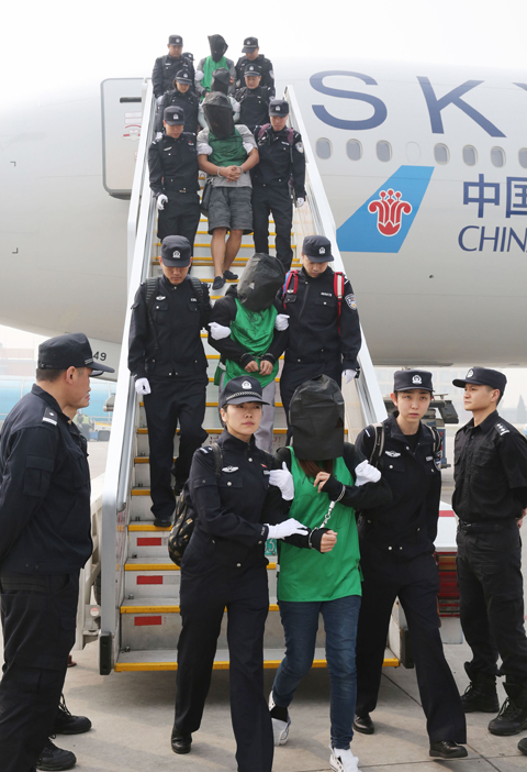 BEIJING: Chinese suspects involved in wire fraud are escorted off a plane at the Beijing Capital International Airport on Wednesday.—AP