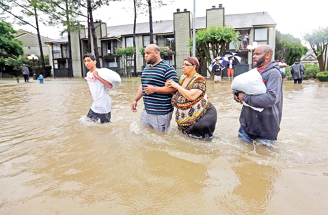 HOUSTON: Darius Simon, second from left, helps his mother Carol, evacuate her flooded apartment complex along with his brother Dominique and son, Isaac Hernandez on Monday.-APn