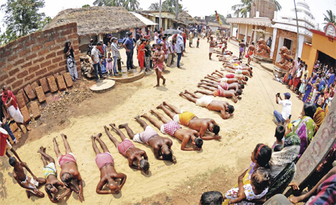 BHUBANESWAR: Indian devotees roll on sand as they offer prayers to the Hindu God Shiva during a ritual as part of The Danda Festival which coincides with The Oriya New Year in the village of Mendhasala Village yesterday. Devotees inflict physical pain on themselves as they perform rituals of penance to appease Shiva, the Hindu God of destruction during the Danda festival, or the festival of self-punishment. — AFP