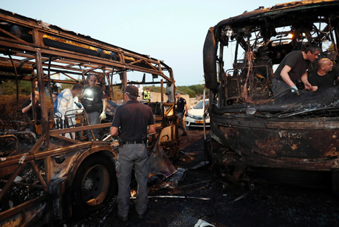 JERUSALEM: Israeli forensic officers search in the remains of burnt-out buses after a bomb blast ripped through the vehicles yesterday. - AFP 
