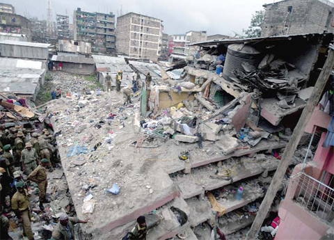 NAIROBI: Kenyan police officers and Kenyan National Youth Servicemen search the site of a building collapse in Nairobi, Kenya yesterday. A six-story residential building in a low income area of the Kenyan capital collapsed Friday under heavy rain and flooding, trapping an unknown number of people in the rubble, Kenyan officials said. — AP