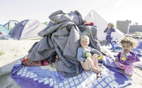 Children sit next to a tent at a makeshift camp for migrants and refugees at the Greek-Macedonian border near the village of Idomeni yesterday. About 50,000 people remain stranded in Greece since the closure of the migrant route through the Balkans in February. Over 10,000 of them are stuck in a slum-like camp at Idomeni on the border with Macedonia.—AFP