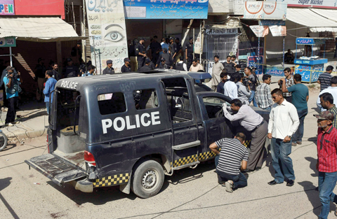 KARACHI: Pakistani security officials inspect a police van after an attack by gunmen on security members guarding a polio vaccination team yesterday. — AFP