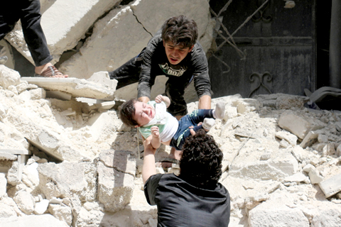 ALEPPO: Syrians evacuate a toddler from a destroyed building following a reported air strike on the rebel-held neighborhood of Al-Kalasa in the northern Syrian city of Aleppo yesterday. — AFP
