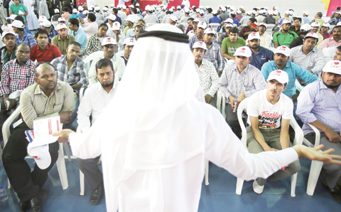 ABU DHABI: A senior administrator from the Dubai Labor Office speaks to several hundred workers gathered at a residential camp for laborers and managers during an event yesterday. - AP 