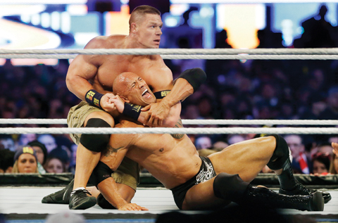 EAST RUTHERFORD: In a Sunday, April 7, 2013 file photo, wrestler John Cena, top, chokes Dwayne Douglas Johnson, known as The Rock as they wrestle during Wrestlemania, in East Rutherford, N.J. WWE bills WrestleMania as its Super Bowl, and is headed to a stadium worthy of a Super Bowl. The WWE has lofty expectations of stuffing 100,000 fans inside AT&T Stadium in Arlington, Texas. - AP