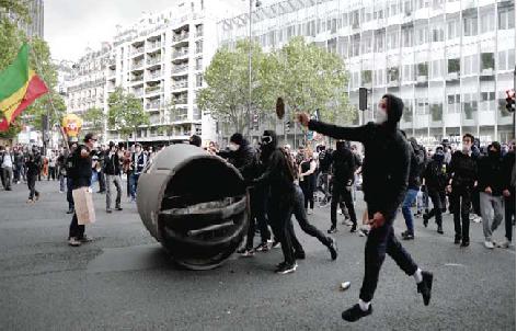 PARIS: A protester sends projectile as others move a pulled down recycling garbage during a demo against the government’s labor reform yesterday. — AFP