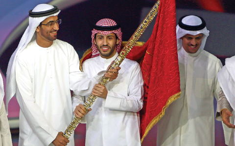 Kuwait’s Rajih Al-Hamidani (center) receives the ‘flag of poetry’ after winning the final of the televised program Million’s Poet at Abu Dhabi’s Al-Raha Theatre. — AFP photos