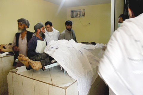KUNDUZ: Afghan relatives stand over the body of the victim of a Taleban attack, in a hospital at the Aliabad district of Kunduz province yesterday. — AFP