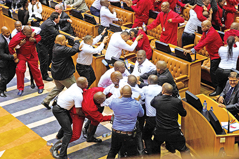 Economic Freedom Fighters (EFF, in red) party members of parliament are physically removed from the South African parliament after repeatedly ignoring the instructions of the Speaker, on May 17, 2016, in Cape Town.nA brutal fistfight broke out in the South African parliament on May 17 as security guards ejected opposition lawmakers in an ugly fracas that underlined heightened political tensions over Jacob Zuma's presidency. / AFP PHOTO / RODGER BOSCH