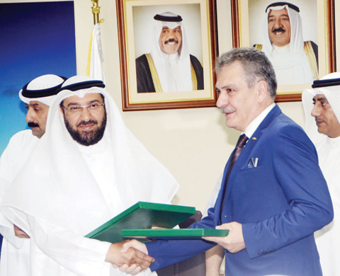KUWAIT: Minister of Public Works and Minister of State for National Assembly Affairs Ali Al-Omair and Vice Chairman of Limak Holding Sezai Bacaksiz exchange documents during the signing ceremony yesterday. — KUNA