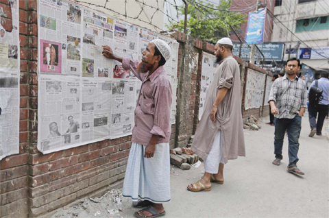 DHAKA: Bangladeshi men read about the execution of Jamaat-e-Islami party chief Motiur Motiur Rahman Nizami, on newspapers, pasted on a wall at an alley.—AP