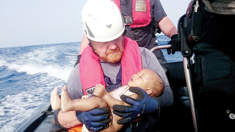 AT SEA: A Sea-Watch crew member holds a drowned baby as dead bodies were recovered after a wooden boat transporting migrants had capsized off the Libyan coast. — AFP
