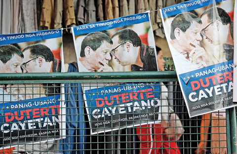 DAVAO CITY: A resident walks past election tarpaulins featuring Philippine presidential candidate and Davao Mayor Rodrigo Duterte displayed on a street. — AFP