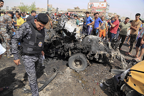 Security forces and citizens inspect the scene after a suicide car bomb hit a crowded outdoor market in Baghdad's eastern Shiite neighborhood of Sadr City, Iraq, Tuesday, May 17, 2016. A wave of bombings struck outdoor markets in Shiite-dominated neighborhoods of Baghdad on Tuesday, killing and wounding dozens of civilians, officials said, the latest in deadly militant attacks far from the front lines in the country's north and west where Iraqi forces are battling the Islamic State group. (AP Photo/Karim Kadim)