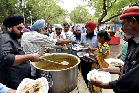 NEW DELHI: Indian residents receive free food donated by a community kitchen on a hot afternoon in New Delhi yesterday. — AFP