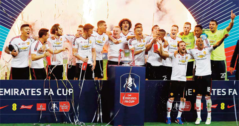 LONDON: United’s manager Louis van Gaal (right) watches as the players pose with the trophy after they won the English FA Cup final soccer match between Manchester United and Crystal Palace at Wembley stadium yesterday. United won 2-1. — AP
