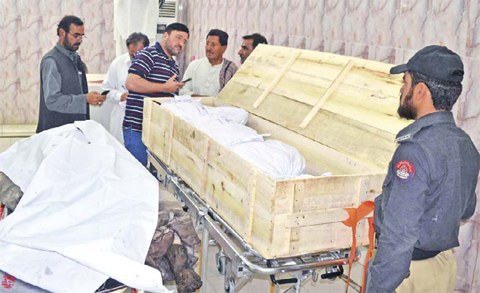 QUETTA, PAKISTAN: Pakistani security officials and hospital staff stand next to unidentified dead bodies placed on stretchers at a morgue in a hospital on Sunday. — AFP
