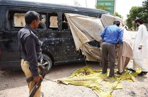 KARACHI: Pakistani security officials examine a damaged vehicle in which a Chinese National was travelling, following a roadside bomb attack. — AFP