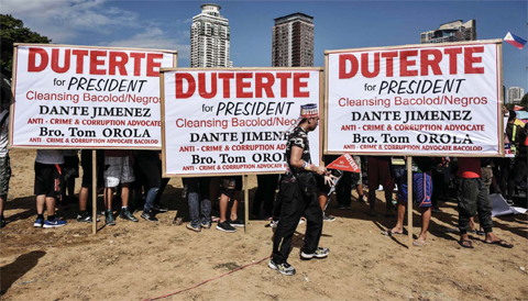 MANILA: A supporter of Presidential candidate and Davao Mayor Rodrigo Duterte walks in front of banners during an election campaign rally ahead of the presidential and vice presidential elections. — AFP