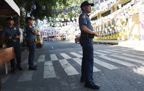 MANILA: Philippine policemen stand guard outside a school to be used as polling station ahead of the presidential election yesterday.-AFP