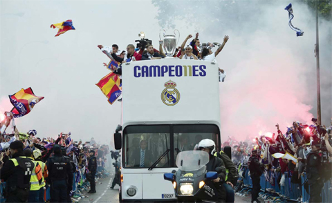MADRID: Fans surround the bus as Real Madrid players hold up the trophy celebrating the team’s win on Plaza Cibeles. — AP
