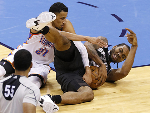 Oklahoma City Thunder guard Andre Roberson, left, reaches for a ball held by San Antonio Spurs forward Kawhi Leonard, right, in the third quarter of Game 6 of a second-round NBA basketball playoff series in Oklahoma City, Thursday, May 12, 2016. (AP Photo/Alonzo Adams)