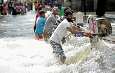 COLOMBO: Flood-affected Sri Lankans struggle to cross a torrent of floodwaters in Kelaniya, on the outskirts of Colombo yesterday. — AFP