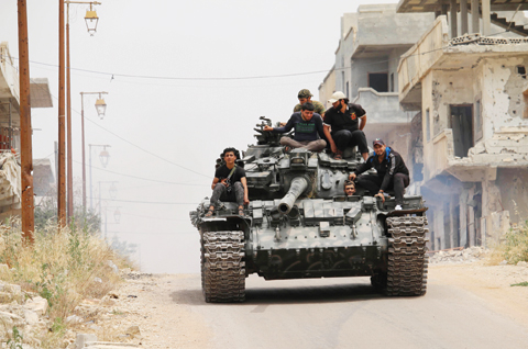 DARAA: Opposition fighters drive a tank in a rebel-held area of the southern Syrian city of Daraa, during re-newed clashes with regime loyalists. — AFP