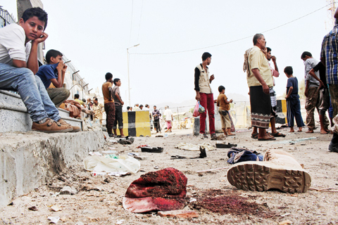 ADEN: People gather at the scene after a pair of suicide bombings in this southern Yemeni city yesterday. — AP