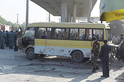 KABUL: Afghan policemen look at the site of a suicide attack to have hit a minibus carrying foreign security guards yesterday. —AFP