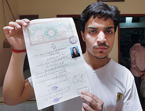 LAHORE: Hassan Khan, husband of Zeenat Rafiq, who was burned alive, allegedly by her mother, shows his marriage certificate to media at his home yesterday. —AP