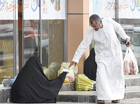 A Saudi man hands money to a woman begging outside a supermarket on a main street in the Saudi capital Riyadh, on June 20, 2016. Charity is one of the main principles of Ramadan, the Islamic holy month when Muslims around the world fast from dawn until dusk. Each Ramadan, which began this year on June 6, many more beggars take to the streets of oil-rich Saudi Arabia, Islam's spiritual home, but this year a leading charity is urging Saudis to channel their generosity elsewhere. / AFP / FAYEZ NURELDINE