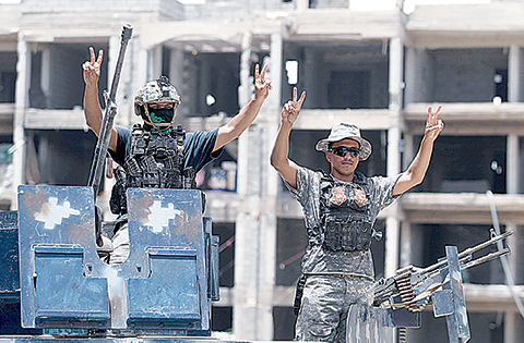 Iraqi government forces members gesture as they stand at the edge of Shuhada neighbourhood, south of Fallujah, during an operation to regain control of the area from the Islamic State (IS) group on June 10, 2016. Iraq's elite counterterrorism service moved to within three kilometres of central Fallujah and consolidated positions in the south of the city, the operation's commander Lieutenant General Abdelwahab al-Saadi said. / AFP / AHMAD AL-RUBAYE