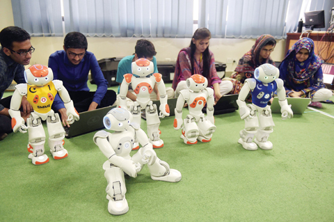 ISLAMABAD: In these photographs taken on May 9, 2016, Pakistani students and team members of Robotics and Intelligence Systems Engineering (RISE) program their robot football players in the engineering department of the National University of Sciences and Technology. — AFP