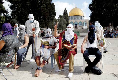 JERUSALEM: Masked Palestinian protesters wearing pieces of cloth around their bodies read the Holy Quran following clashes with the Israeli police at Jerusalem’s Al-Aqsa mosque compound for the third consecutive day yesterday. Israeli authorities announced they were closing the Al-Aqsa mosque compound to non-Muslim visitors. The decision will apply until the end of the holy month of Ramadan next week. —AFP