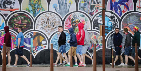 LENS: Football supporters walk past a piece of street art as they walk in heavy rain in Lens, northern France, yesterday, on the day England plays against Wales in their Euro 2016 group B football match. — AFP