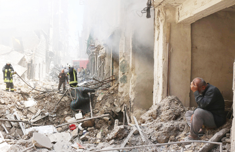 ALEPPO: A man sits on the rubble of a destroyed building following reported air strikes by government forces in the rebel-held Shaar neighborhood of the northern city Aleppo yesterday. -AFP 