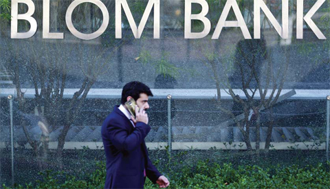 BEIRUT: Photo shows a man talking on his mobile phone as he walks past the sign of the BLOM BANK in the Lebanese capital Beirut. A bank crackdown on hundreds of accounts linked with Hezbollah is raising tensions in Lebanon, where the powerful Shiite movement enjoys fierce support and provides a range of social services. — AFP