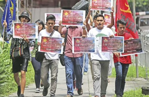 MANILA: Filipino activists hold slogans as they walk towards the Chinese consulate to protest China’s territorial claim over the disputed Spratlys island group during a rally at the financial district of Makati yesterday. — AP