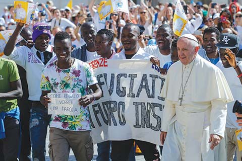 FILE- In this file photo dated Wednesday, June 22, 2016, Pope Francis walks with a group of refugees he invited to join him on the steps of St. Peter's Basilica during his weekly general audience in St. Peter's Square at the Vatican.  Pope Francis begins a five-day visit to Poland on upcoming Wednesday July 27, 2016, and hopes to inspire aid to homeless strangers and acts of mercy for refugees during his visit, although Poland has closed its borders to refugees. (AP Photo/Fabio Frustaci, FILE)
