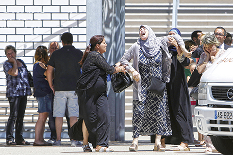 A woman reacts after learning of the death of a relative, outside the Pasteur hospital in Nice, southern France, Saturday, July 16, 2016. The man responsible for turning a night of celebration into one of carnage in the seaside city of Nice was a petty criminal who hadn't been on the radar of French intelligence services before the attack.(AP Photo/Claude Paris)