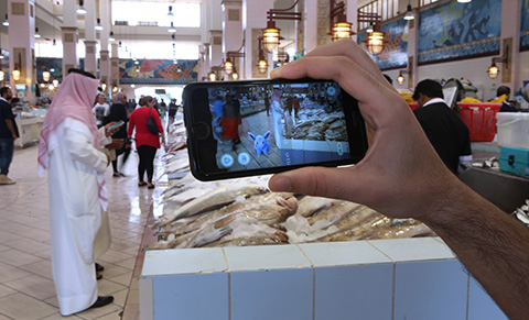 A man tries to catch the pokèmon  'Nidoran' using the app 'Pokèmon Go' in the main fish market in Kuwait City on July 14,2016.