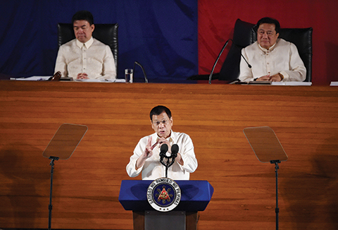 Philippine President Rodrigo Duterte (C) gestures as he delivers his State of the Nation Address at Congress in Manila on July 25, 2016.nDuterte announced a unilateral ceasefire with communist rebels who are waging one of Asia's longest insurgencies, and urged them to reciprocate. / AFP PHOTO / TED ALJIBE