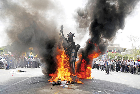 TOPSHOT - A statue depicting US' Statue of Liberty decorated with a Star of David on its head is set ablaze by Iranian protestors during a parade marking al-Quds (Jerusalem) Day in Tehran on July 1, 2016. Tens of thousands joined pro-Palestinian rallies in Tehran, as the annual Quds Day protests take on broader meaning for a region mired in bitter disputes and war. nn / AFP / ATTA KENARE
